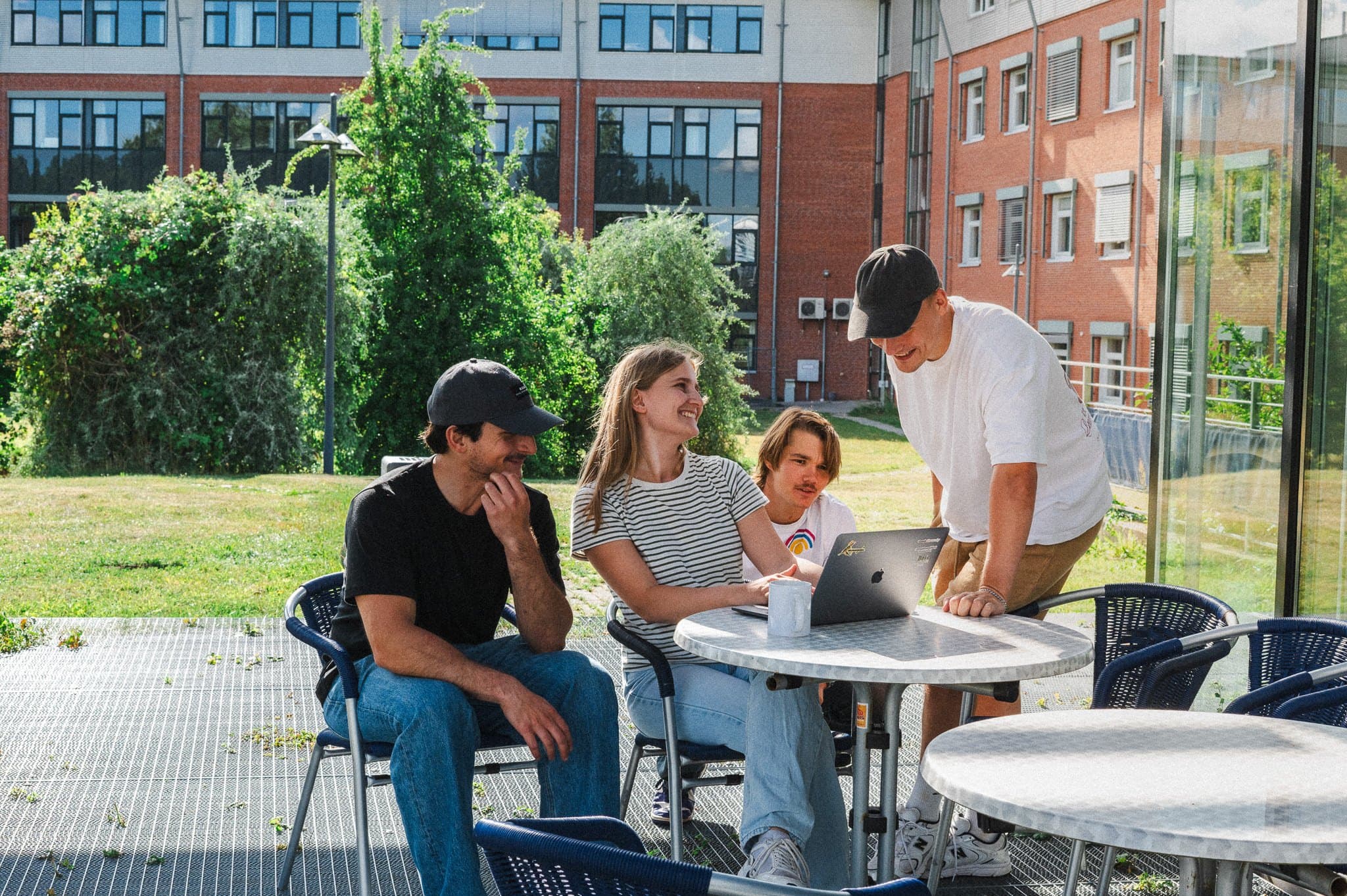 Gruppe trifft sich draußen an einem Tisch auf dem Campus